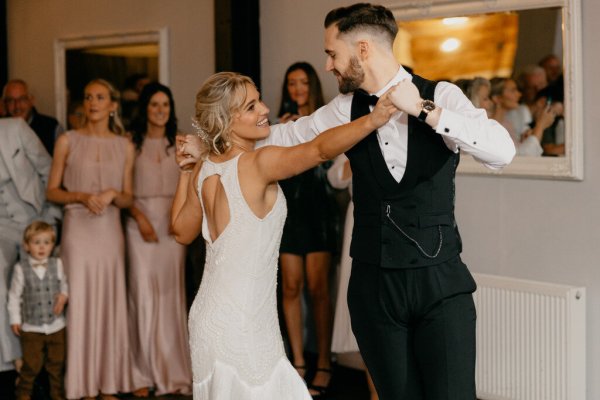 Bride and groom on dancefloor dancing guests watch