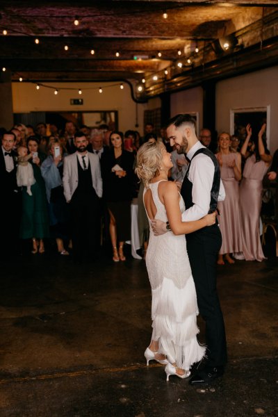 Bride and groom on dancefloor dancing guests watch