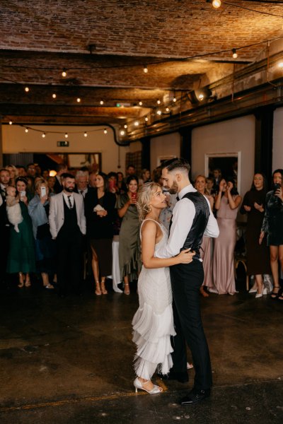 Bride and groom on dancefloor dancing guests watch