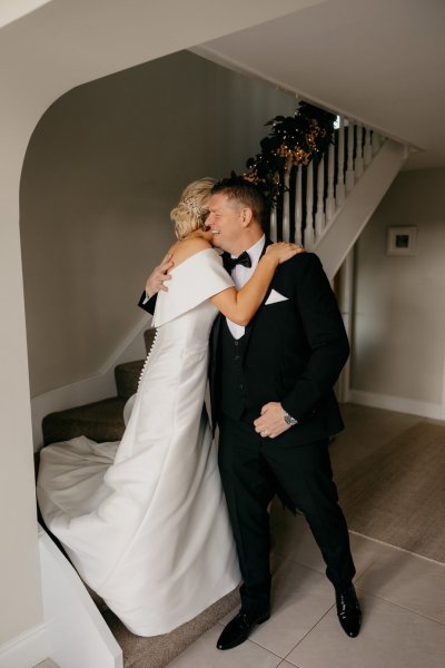 Bride coming down the staircase dad waiting for her hugging and embracing