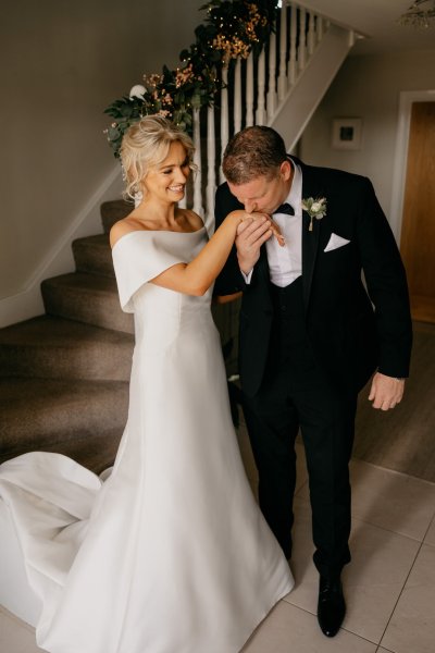 Bride coming down the staircase dad waiting for her hugging and embracing kisses brides hand