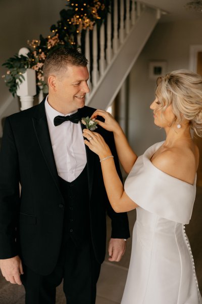 Bride and dad fixing flower on suit