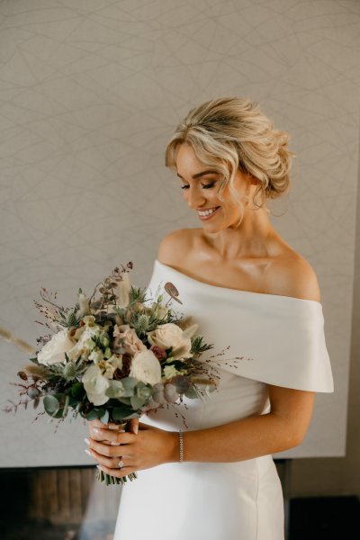 Bride looking down at flowers/bouquet roses smiling