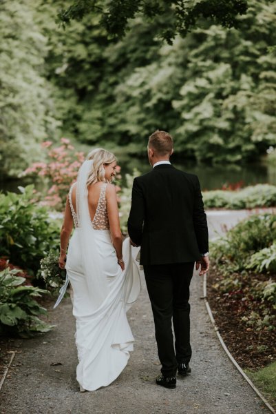 Bride and groom walking along forest pathway