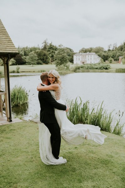 Groom swings bride in air lake setting