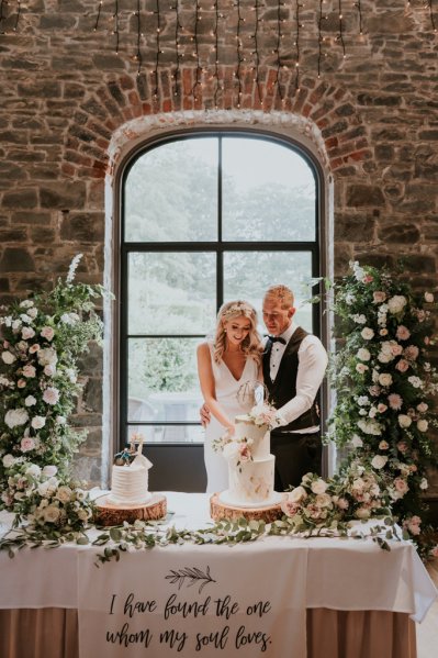 Bride and groom cutting the white wedding cake