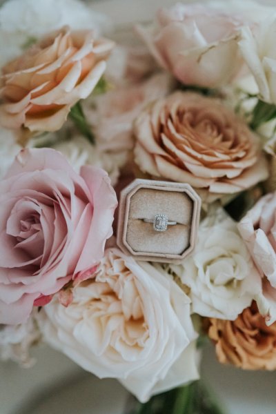 Close up of white and pink roses/flowers with diamond ring/band in the middle