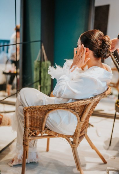 Bride wearing feather sleeved bridalwear sitting on chair