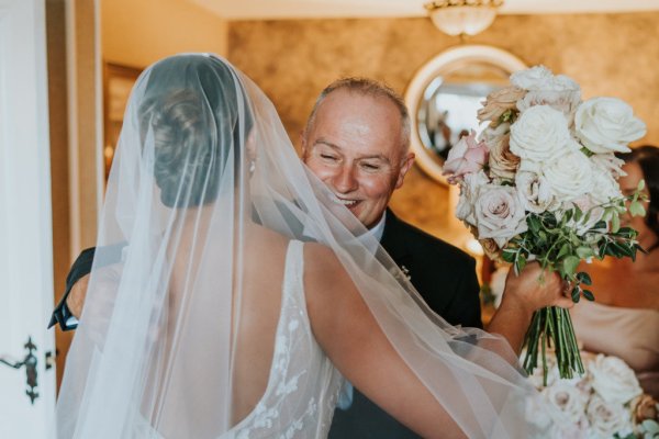 Father of the bride hugs embraces daughter