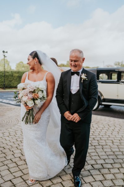 Father of the bride walks into church ceremony wedding car in background