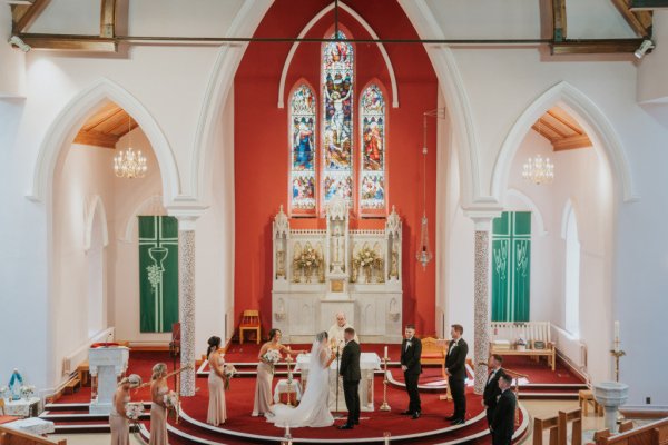 Church setting alter bride groom priest bridesmaids and groomsmen