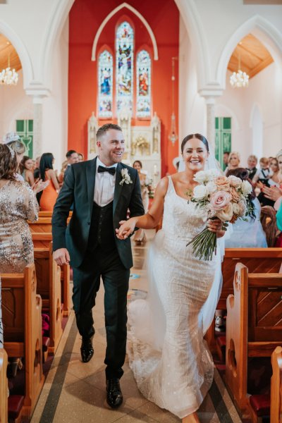 Bride and groom exit church just wed guests clap clapping