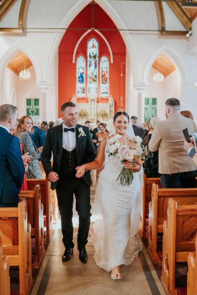 Bride and groom exit church just wed guests clap clapping