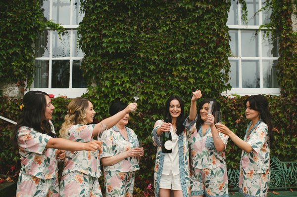 Bride and bridesmaids pop the champagne outside