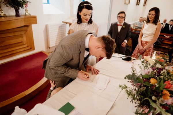 Bride and groom signing wedding certificate table