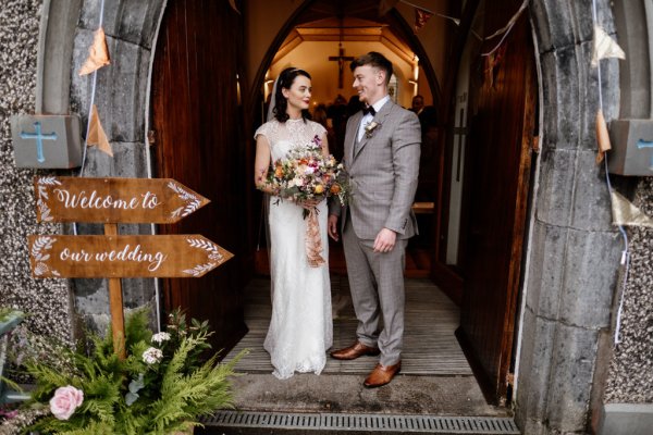 Bride and groom stand at the entrance to the church