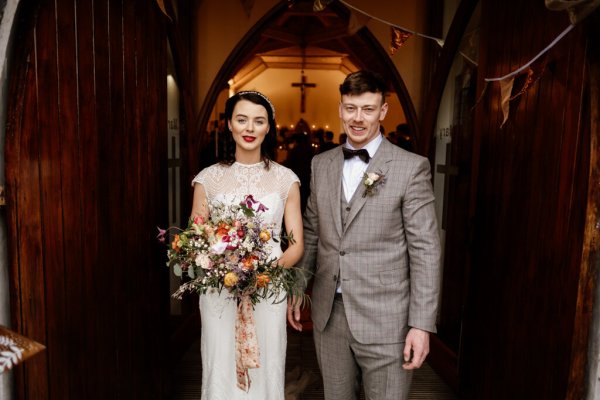 Bride and groom stand at the entrance to the church