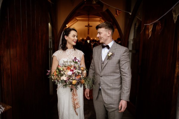 Bride and groom stand at the entrance to the church