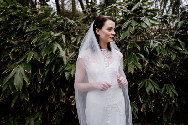 Bride in front of trees in forest park veil detail