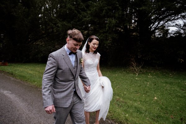 Bride and groom walk on the pathway in forest/park