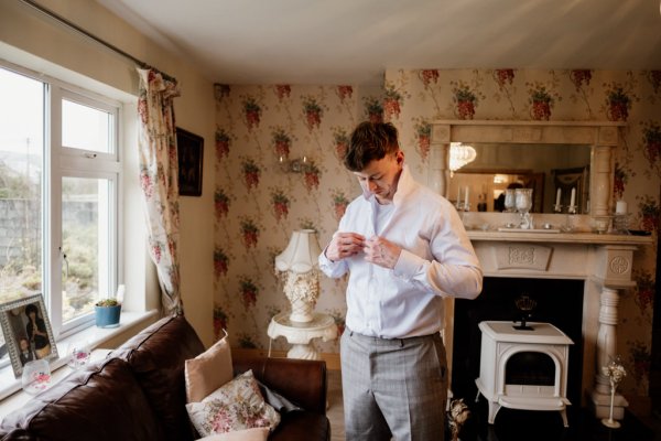 Groomsman putting shirt on for wedding