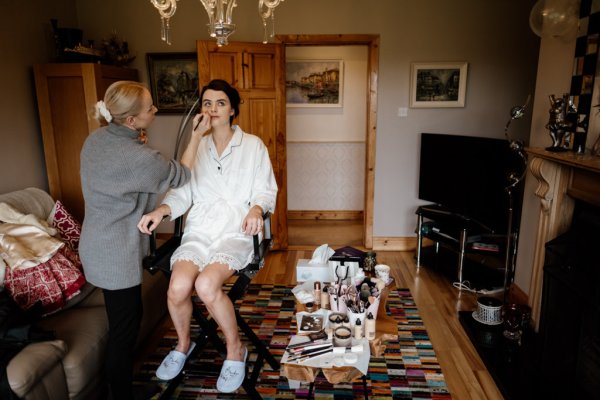 Bride getting her makeup done MUA interior bedroom