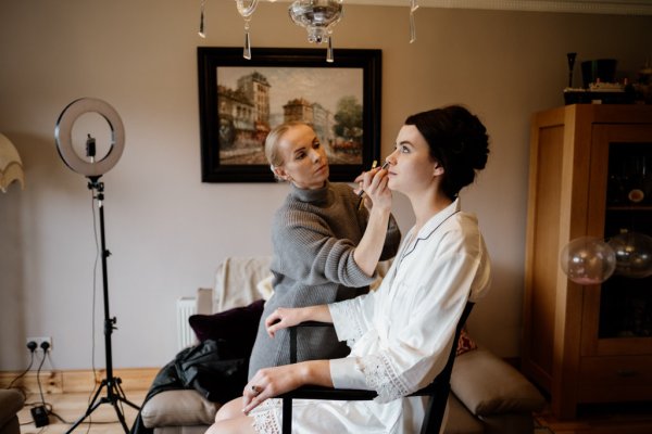 Bride getting her makeup done MUA interior bedroom