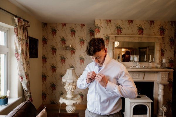 Groomsman putting shirt on for wedding