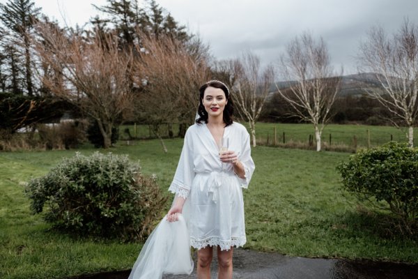 Bride holding glass of champagne prosecco park tree forest setting