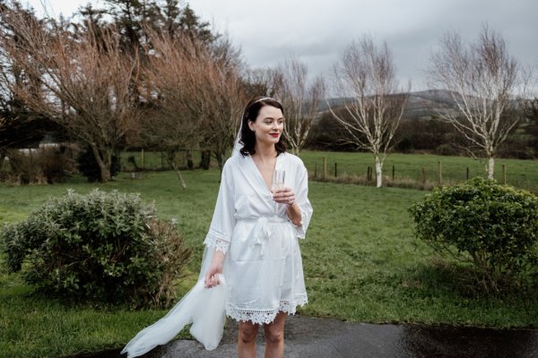 Bride holding glass of champagne prosecco park tree forest setting