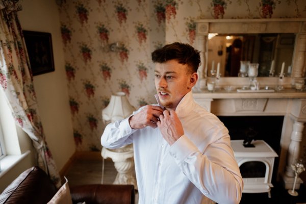 Groomsman putting shirt on for wedding