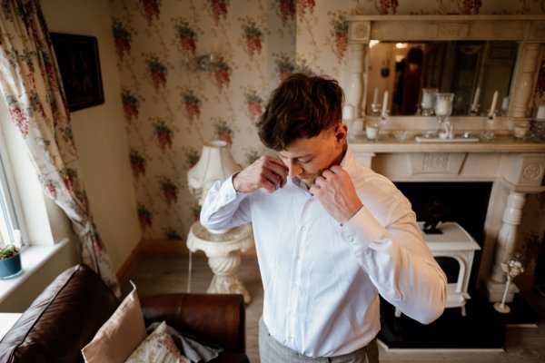 Groomsman putting shirt on for wedding