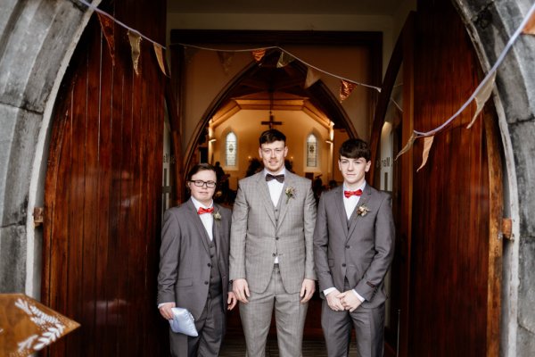 Groom and groomsmen in suits church exterior entrance