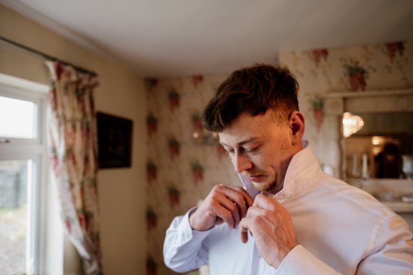 Groomsman putting shirt on for wedding