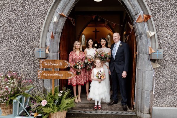 Family shot bride little girl father and mother flowers exterior church setting