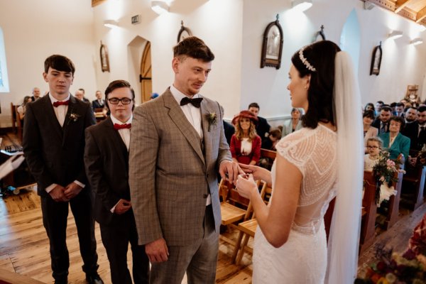 Bride puts wedding band/ring on grooms finger