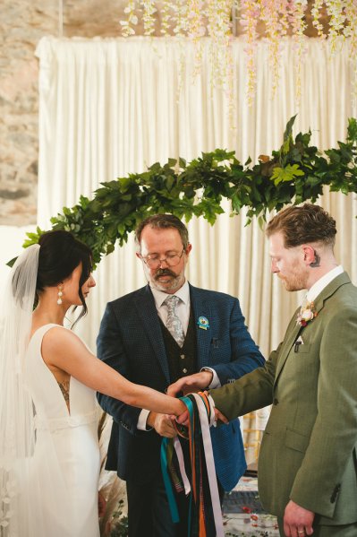 Officiant bride and groom bound ribbon on hands