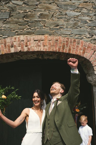 Groom punching the air with bride