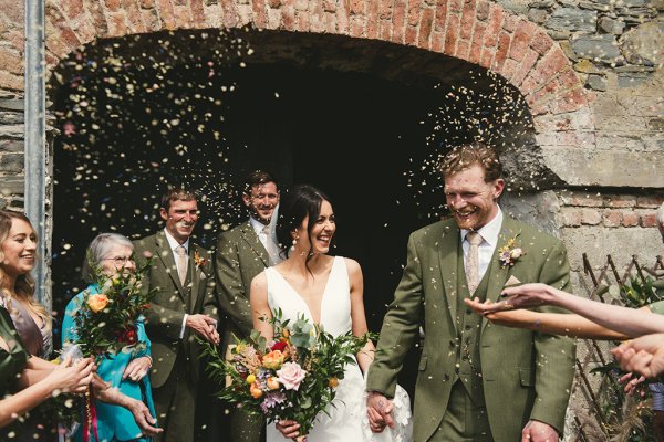 Bride and groom guests throwing confetti over couple