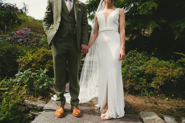 Bride and groom hold hands in garden