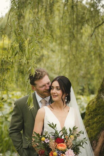 Bride and groom laugh in garden