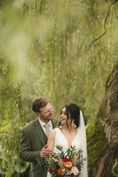 Bride and groom laugh in garden