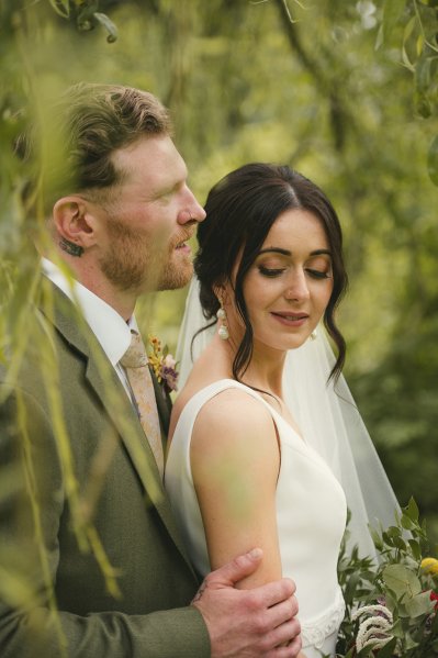 Bride and groom in garden tree looking down