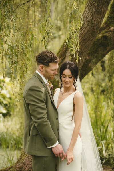 Bride and groom in garden tree looking down