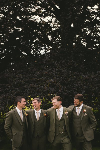 Groom and groomsmen pose for a picture in a park