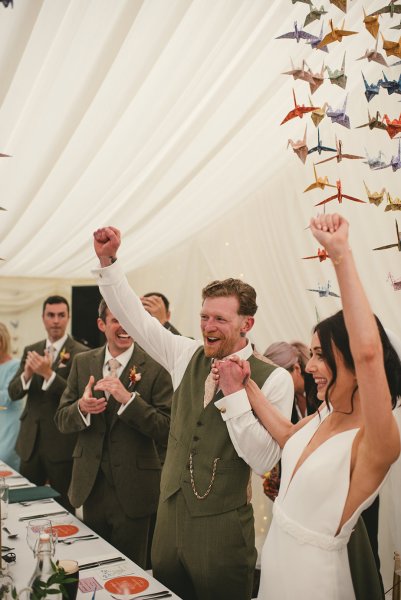 Bride and groom hands in the air celebrating guests clapping