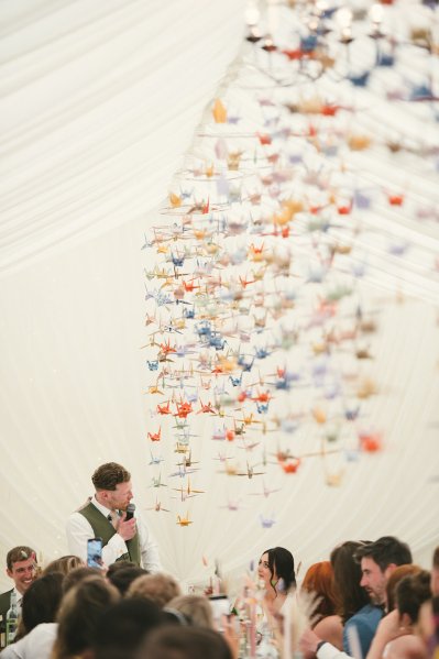 Groom in green suit during his speech looking at bride