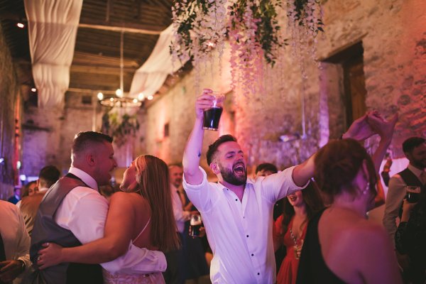 Man in white shirt holding Guinness sings along to songs on dancefloor