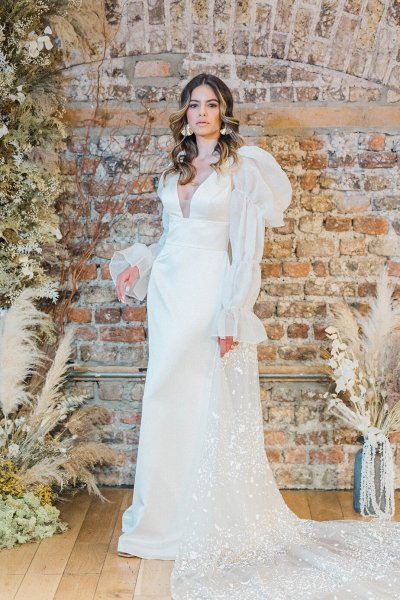 Flower detail bricked wall on wooden table bride standing puffy shoulder bridal dress/gown