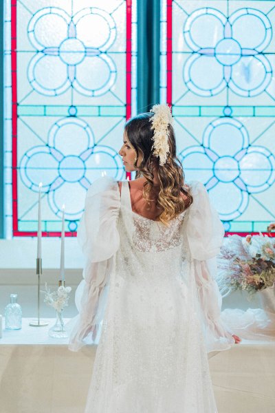 Bride standing at table looking over the shoulder in front of window table dining room setting